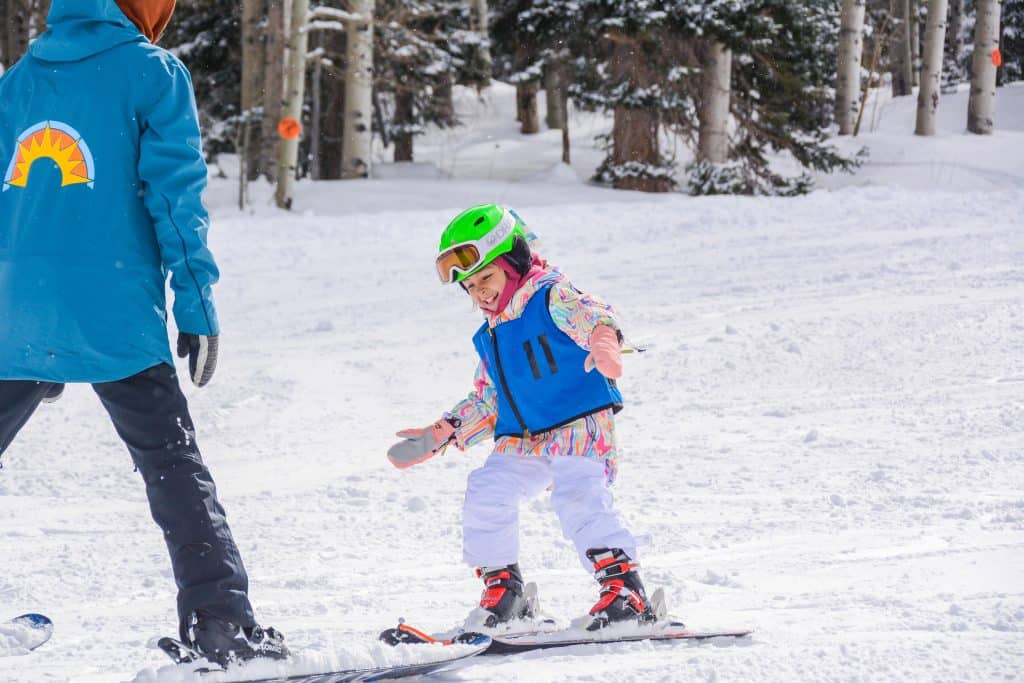 A child in ski school skis down a snowy mountain