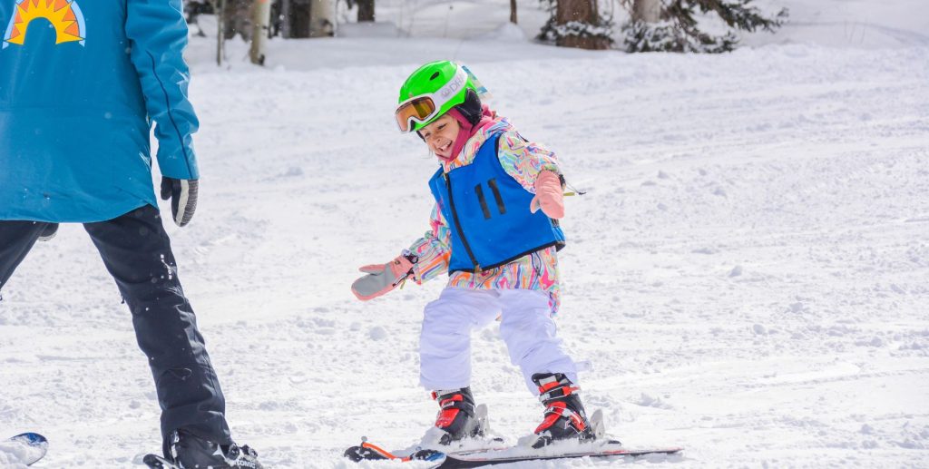 A child in ski school skis down a snowy mountain